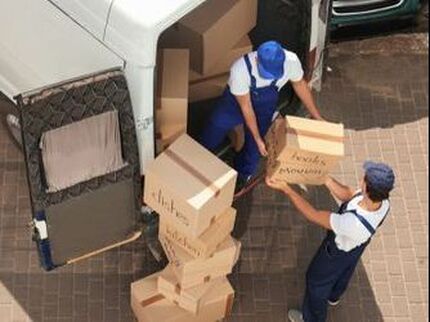 two moving professionals loading card board boxes into a van